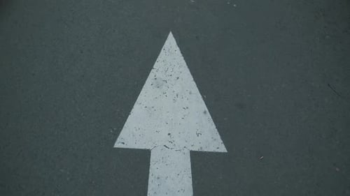 Indonesian white arrow road sign on an asphalt road.