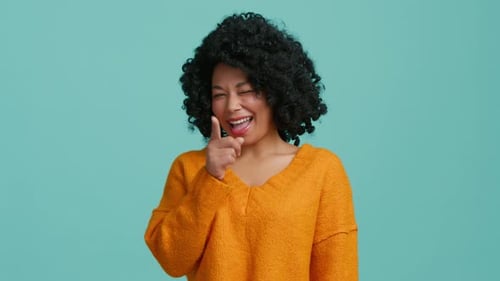 Fröhliche Frau fühlt sich glücklich zeigt mit dem Finger auf Sie vor der Kamera und zwinkert positiv