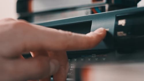 Hand Inserts VHS Tape into VCR Player