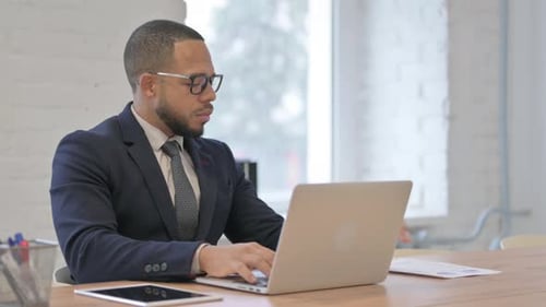 Man in Suit Typing on Laptop in Office