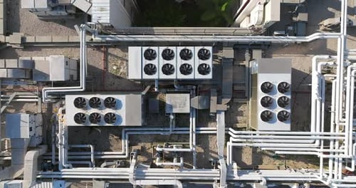 Industrial building rooftops with vents and pipes lined across, Top down view