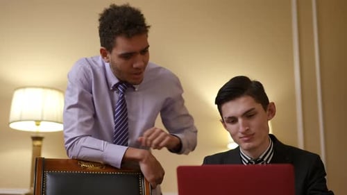 Deux professionnels qualifiés travaillant ensemble sur un ordinateur portable dans un environnement de bureau moderne