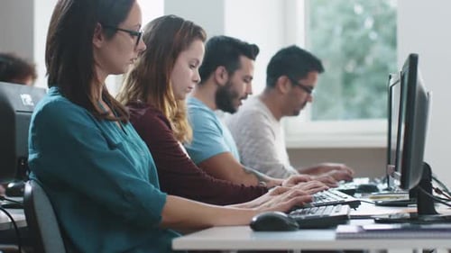 Group of Mixed Race Students are sitting in a Row and Working on Computers.