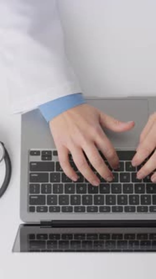 Hands Type on Laptop with Stethoscope and Charts