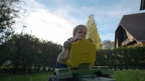 Child Playing with Tractor Toy in the Yard