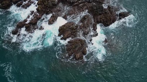 A captivating drone shot captures the dramatic beauty of rocky stones scattered along the shore, wit