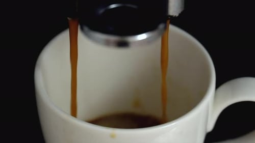 Coffee machine pouring black espresso, close up