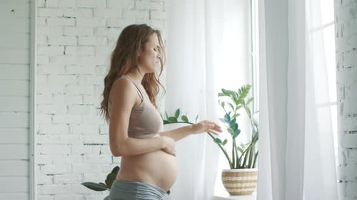 Die
werdende Mutter fühlt sich zu Hause schwanger und hat Schmerzen. Nahaufnahme Traurige schwangere Frau stehend
