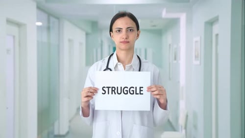 Serious Doctor Holding a Struggle Sign in Hospital