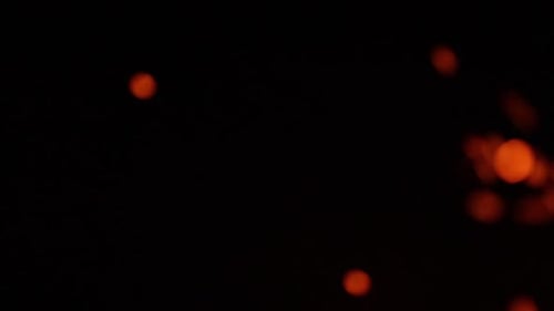 Faszinierendes Feuerflammen-Bokeh, das in der Nacht im Wind tanzt, dunkler Hintergrund