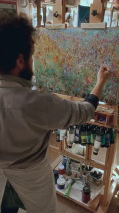 Artist Painting Abstract Picture on Canvas Propped Up on Easel in Studio