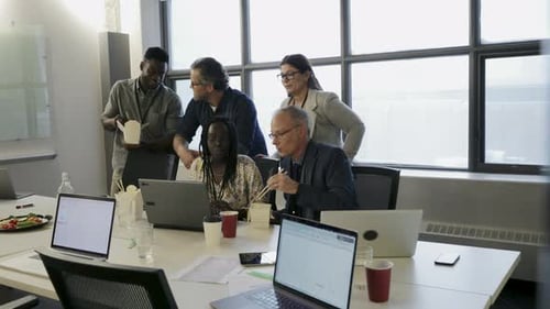 Colleagues Gather Around Laptop During Lunch Break