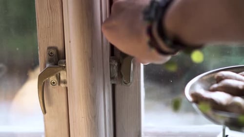 Man opening window during sunny day.