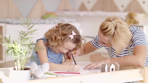 Woman and child drawing together at table indoors