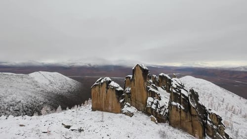 Experience a breathtaking aerial journey over towering rock formations and snow-laden mountains in a