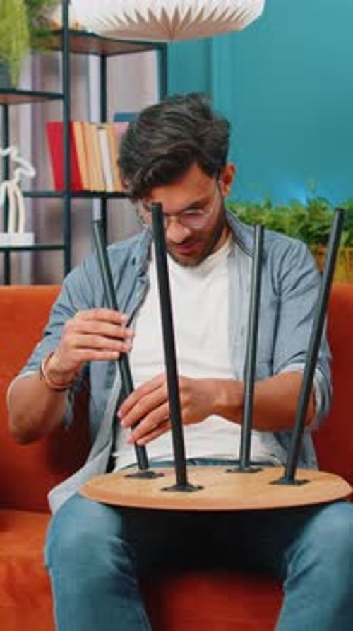 Young Man Assembling Small Table in Living Room