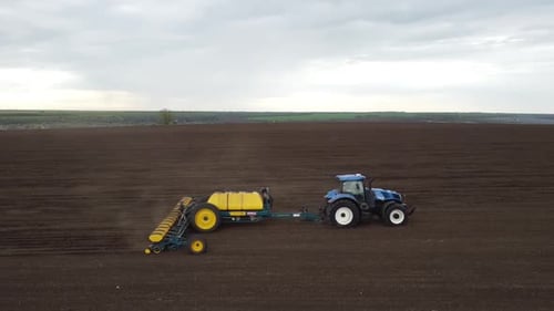 Blauer Traktor OA arbeitet auf dem Feld in der Ukraine