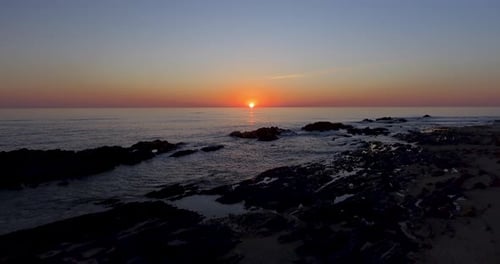 4k Pull away aerial shot of a beautiful sea coast at sunset