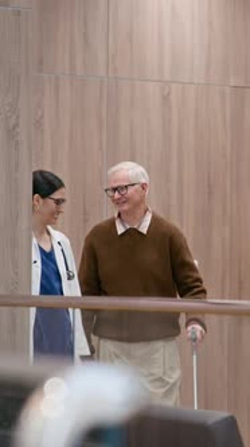 Physician Assisting Elderly Patient with Crutch in Clinic Hall, Vertical