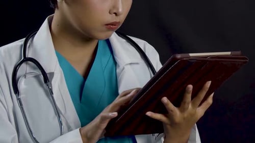 Female doctor or nurse looking at a patient's data on a tablet - close, tight framing