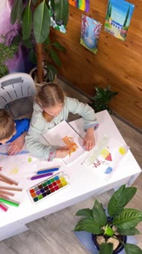 Children Drawing Together at Table Indoors