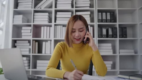 Businesswoman is talking to clients and colleague on the phone and working on laptop in office