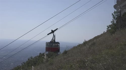 The red cable car is moving up with the people in the background of the city Pyatigorsk