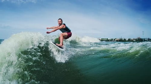 Wakesurfing. Man rides the boat's wake on the freshwater lake at sunny day