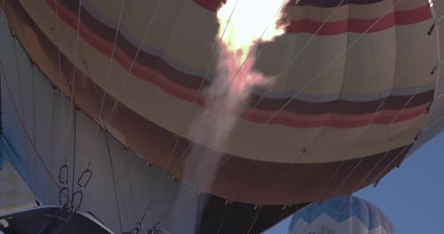 Hot Air Balloon Inflating with Flame Against Blue Sky