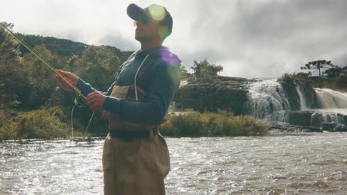 Man Fishing in River with Waterfall Background