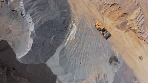 Bulldozer bewegt sich zwischen großen Kieshaufen.