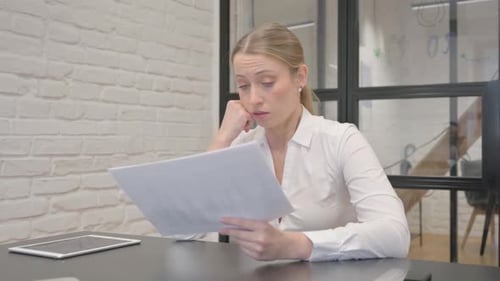 Worried Woman Reviews Documents at Office Desk