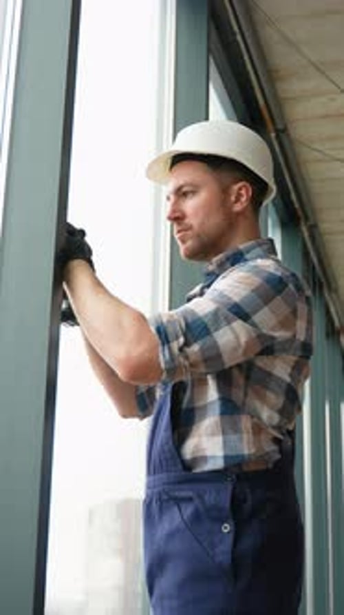 Construction Worker Installing Window in Building