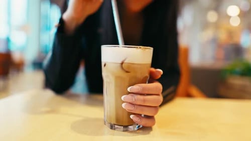 Woman stirring foamy iced coffee at cafe