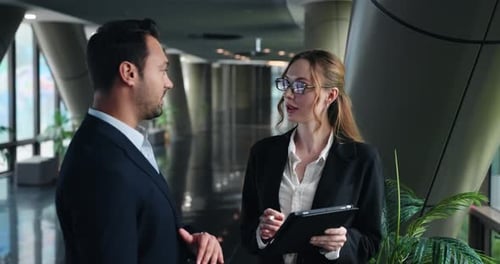 Businesspeople In Suits Converse Seriously In An Office Lobby. - medium shot