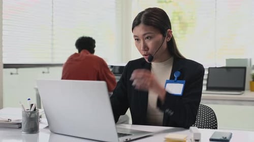 Specialist of Call Centre Talking with Client while Sitting at Laptop in Office