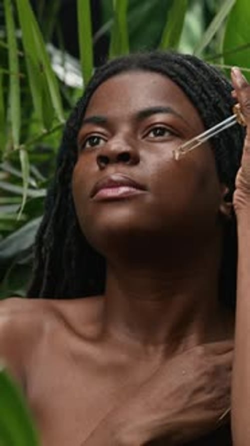 Woman Applying Facial Oil in Tropical Setting