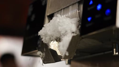 Close-up video of an ice making machine producing crushed ice flakes