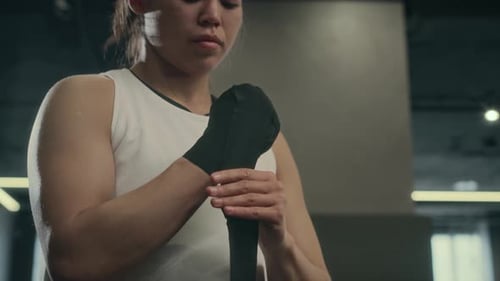 Woman Wrapping Hands for Boxing Training in Gym