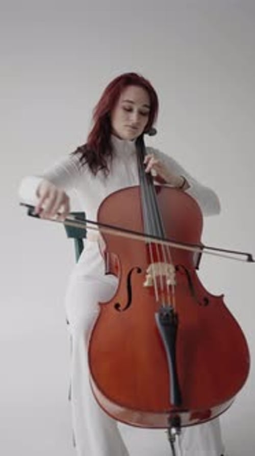 Woman Plays Cello Sitting Down in White Room