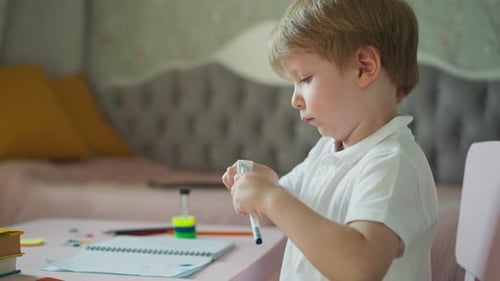 Niño juega con bolígrafo y goma de borrar sentado en el escritorio
