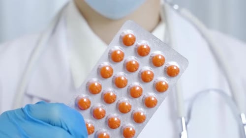 Medical Professional Holding Blister Pack of Orange Pills