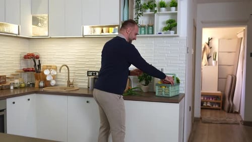 Man Unpacks Grocery Bag in Modern Kitchen