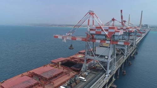 Riesiges Frachtschiff, das im Industriehafen angedockt ist und von Kränen beladen wird