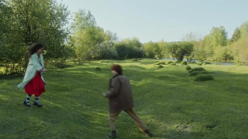Joyful Couple Having Fun in Green Meadow in Sunny Day