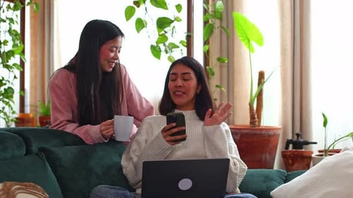 Two young women chatting on sofa at home
