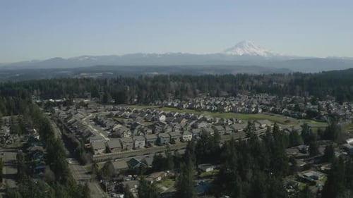 Scenic View Of Rows Of Houses And Lush Pine Trees In A Village In Puyallup, Washington With Snowy Mt
