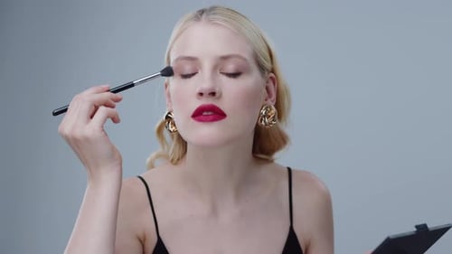 Glamorous woman applying eye shadow with brush
