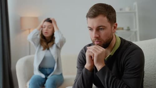 Stressed Man with Arguing Woman in Background