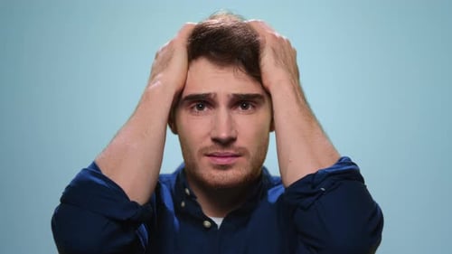 Portrait of Stressed Man Touching Head with Hands in Studio. Worried Person